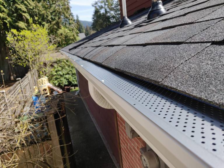 Leaf guard fitted to a gutter below an asphalt shingle roof